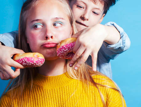 happy family brother and sister eating donuts on blue background, lifestyle people concept, boy and girl eating unhealthy foodの写真素材