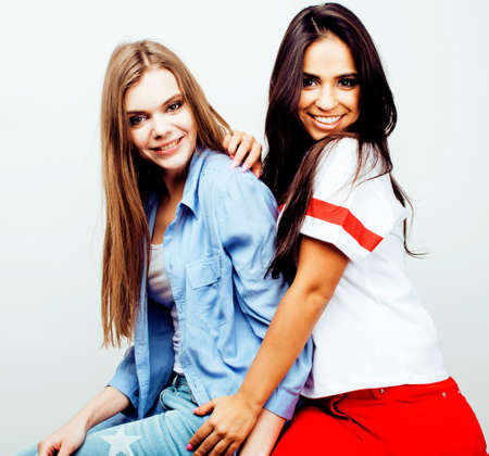 best friends teenage girls together having fun, posing emotional on white background, besties happy smiling, lifestyle people concept, blond and brunette multi nationsの写真素材