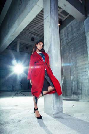 young pretty african american woman in luxury red coat posing fashionable on empty parking building, lifestyle rich people conceptの写真素材