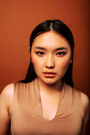 young pretty asian woman cheerful smiling posing on warm brown background, lifestyle people conceptの写真素材
