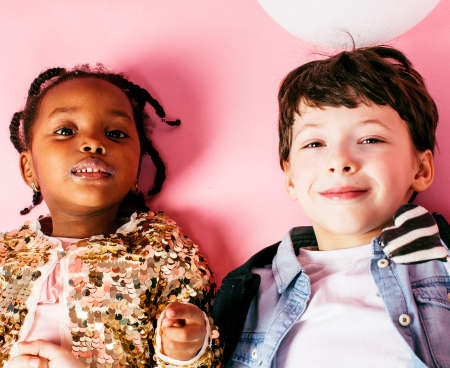 lifestyle people concept: diverse nation children playing together, caucasian boy with african little girl holding candy happy smilingの写真素材