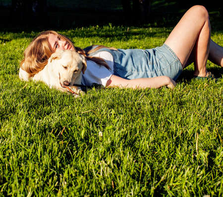 young attractive blond woman playing with her dog in green park at summer, lifestyle people concept, true friendshipの写真素材