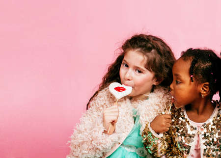 lifestyle people concept: diverse nation children playing together, caucasian boy with african little girl holding candy happy smilingの写真素材