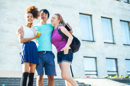 cute group of teenages at the building of university with books huggings, diversity nations, having lunchの写真素材