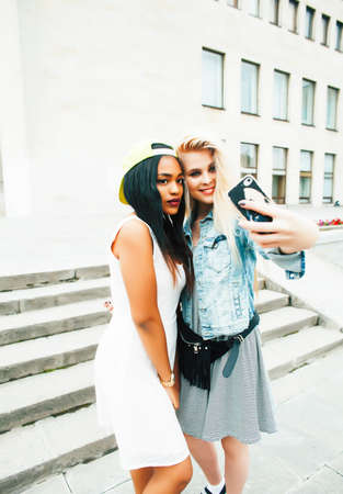 Two teenage diverse nations girls infront of university building smiling, having fun traveling europe, lifestyle people conceptの写真素材