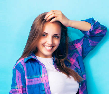 young pretty girl posing happy smiling on blue background, lifestyle people on summer vacation conceptの写真素材