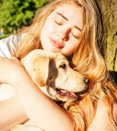 young attractive blond woman playing with her dog in green park at summer, lifestyle people concept, true friendshipの写真素材