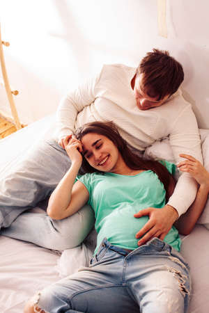 young caucasian pregnant couple together at home relaxing in bed, lifestyle people conceptの写真素材