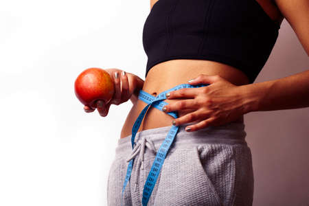 woman measuring waist with tape on knot, african tan isolatedの写真素材