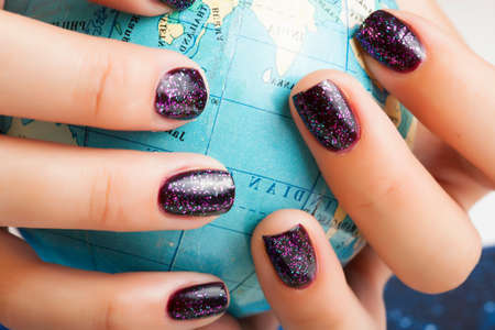 woman hands with purple manicure holding Earth ball, global planet issues conceptの写真素材