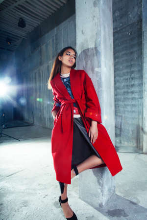 young pretty african american woman in luxury red coat posing fashionable on empty parking building, lifestyle rich people conceptの写真素材