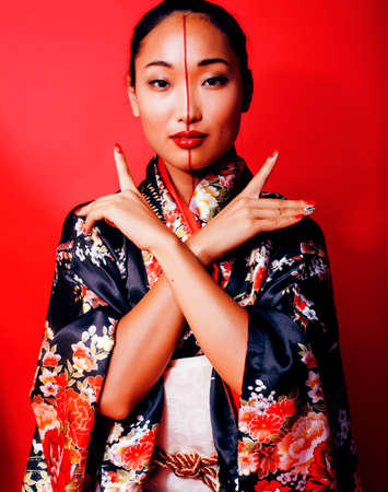 young pretty geisha on red background posing in kimono, orientalの写真素材