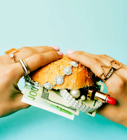 woman hands holding hamburger with money, jewelry, cosmeticの写真素材