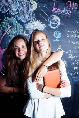 back to school after summer vacations, two teen girls in classroom with blackboard paintedの写真素材
