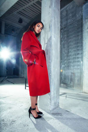 young pretty african american woman in luxury red coat posing fashionable on empty parking building, lifestyle rich people conceptの写真素材