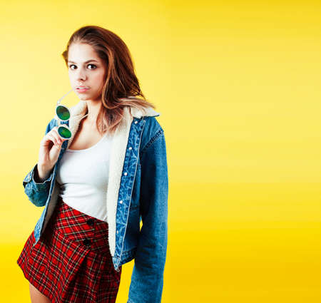 lifestyle people concept: pretty young school teenage girl having fun happy smiling on yellow backgroundの写真素材