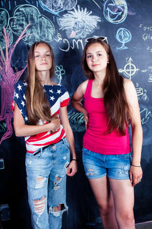 back to school after summer vacations, two teen girls in classroom with blackboard paintedの写真素材