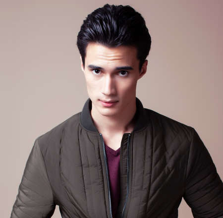young pretty asian man posing in fashion style on light brown background, lifestyle people conceptの写真素材