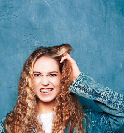 young pretty girl posing happy smiling on blue background, lifestyle people on summer vacation...