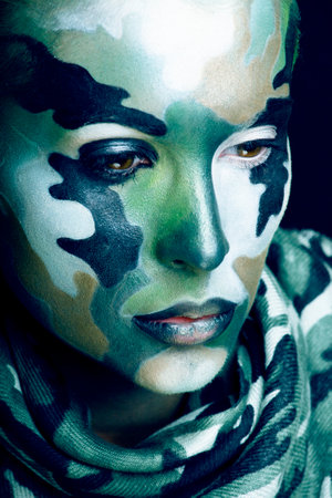 Beautiful young fashion woman with military style clothing and face paint make-up, khaki colors, halloween celebrationの写真素材
