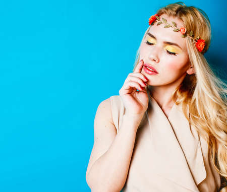 young blond woman dressed like ancient greek godess, beautiful girl hands manicured red nails on blue background copyspaceの写真素材