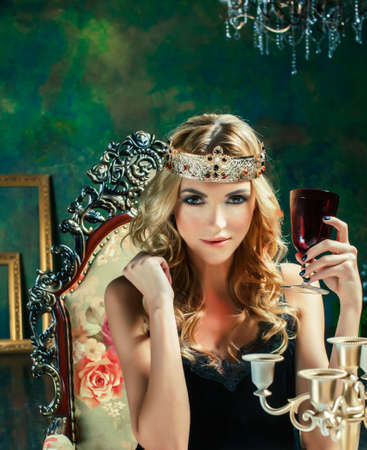 young blond woman wearing crown in fairy luxury interior with empty antique frames total wealth, rich lifestyle conceptの写真素材