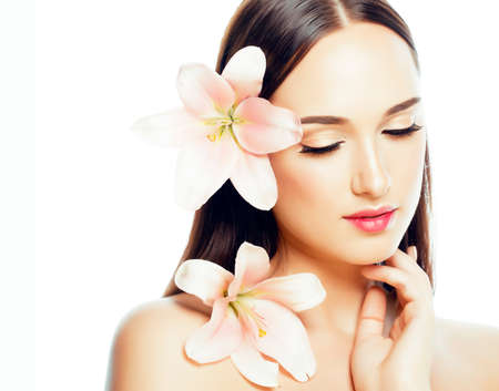 young attractive lady close up with hands on face isolated flower lily brunette spa nude makeup, beauty conceptの写真素材