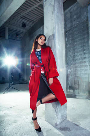 young pretty african american woman in luxury red coat posing fashionable on empty parking building, lifestyle rich people conceptの写真素材