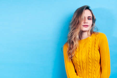 young pretty girl posing happy smiling on blue background, lifestyle people on summer vacation conceptの写真素材