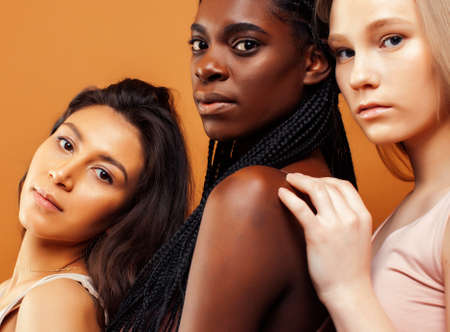 young pretty african and caucasian women posing cheerful together on brown background, lifestyle diverse nationality people conceptの写真素材