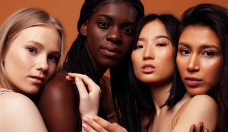 young pretty african and caucasian women posing cheerful together on brown background, lifestyle diverse nationality people conceptの写真素材