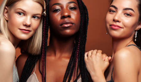 young pretty african and caucasian women posing cheerful together on brown background, lifestyle diverse nationality people conceptの写真素材