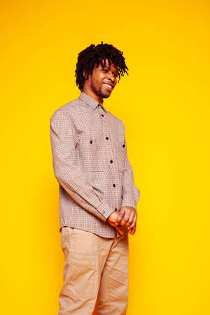 Young handsome african american guy student posing cheerful and gesturing on yellow background, lifestyle people conceptの写真素材