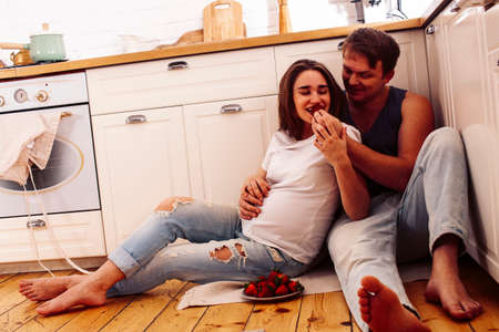 young caucasian couple together having fun on kitchen, woman pregnant, lifestyle people conceptの写真素材