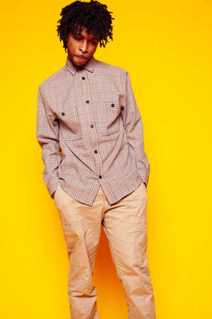 Young handsome african american guy student posing cheerful and gesturing on yellow background, lifestyle people conceptの写真素材