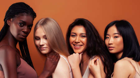 young pretty african and caucasian women posing cheerful together on brown background, lifestyle diverse nationality people conceptの写真素材