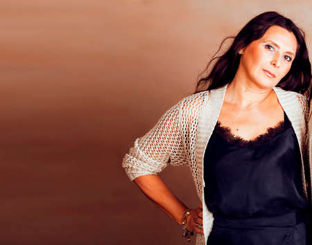 pretty brunette confident mature woman posing cheerful on warm brown background, lifestyle people conceptの写真素材