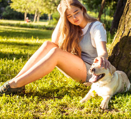 young attractive blond woman playing with her dog in green park at summer, lifestyle people concept, true friendshipの写真素材