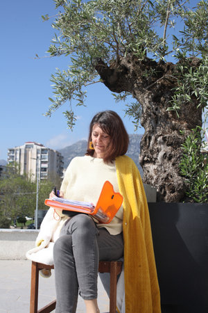 an adult woman on terrace making notes, working with phoneの写真素材