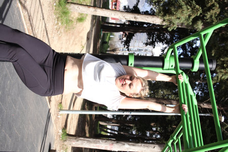 an adult woman doing stretching exercises outside in green park