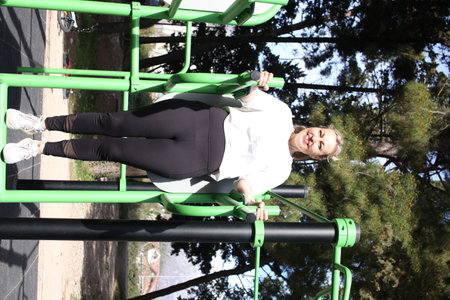 an adult woman doing stretching exercises outside in green parkの写真素材