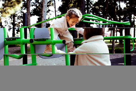 little cute girl with her mother and twin sister having fun on training playground outside