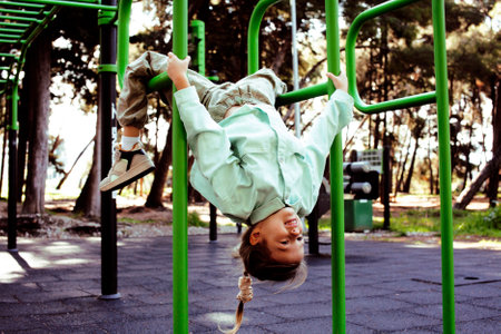 little cute girl with her mother and twin sister having fun on training playground outsideの写真素材
