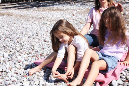 mother with twins daughters on beach