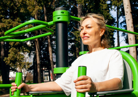 an adult woman doing stretching exercises outside in green park, mental setting training