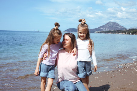 mother with twins daughters on beach