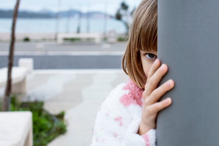 little cute blond girl curious smiling playing outside on seaの写真素材