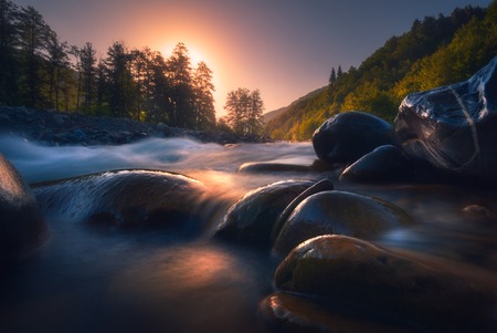 beautiful sunrise over fast flowing mountain riverの写真素材