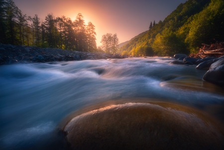 beautiful sunrise over fast flowing mountain riverの写真素材