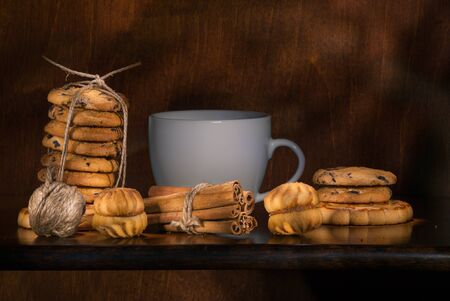 Christmas concept with a cup of hot tea, cookies and decorations on a log over wooden background,...